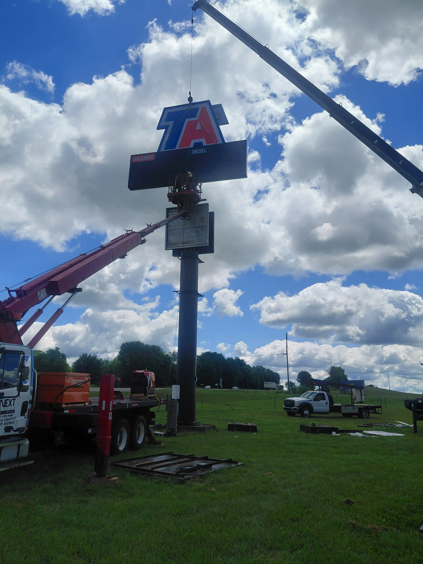 BNext Design cranes installing a TA high-rise fuel price sign beneath a blue sky