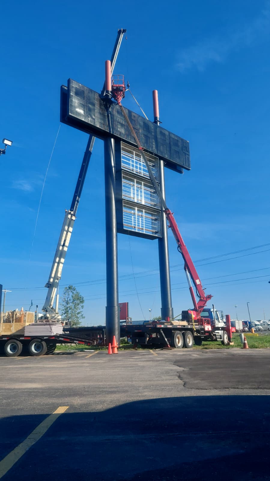 BNext Design service equipment and cranes working on a large black pylon sign structure