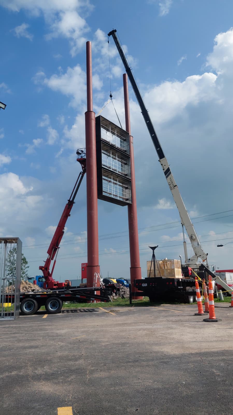 BNext Design lifting structural high-rise sign cabinets between tall steel poles